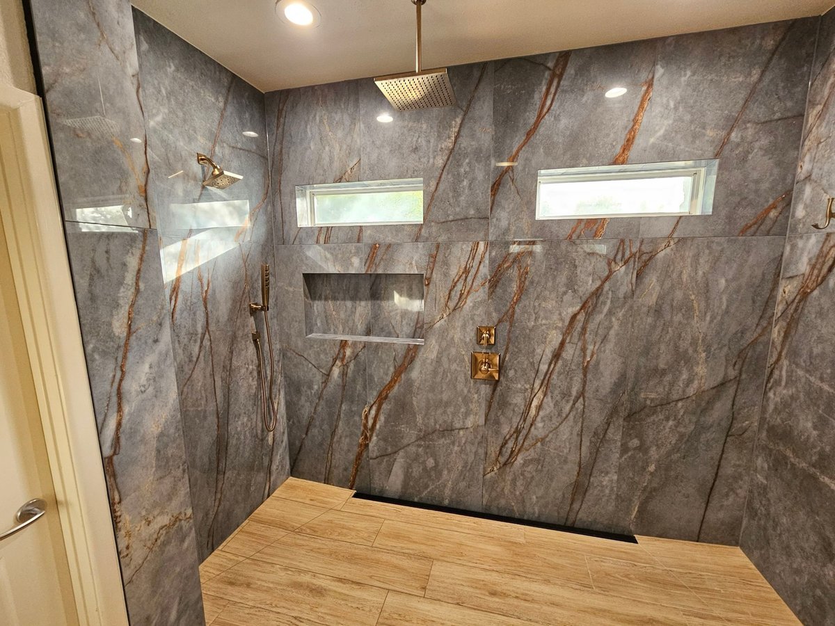Marble shower with rainfall head, gold fixtures and high windows