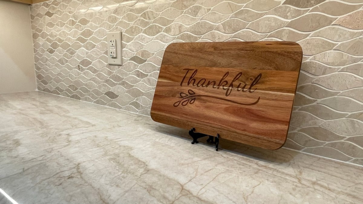 Close-up of veined marble countertop and arabesque tile backsplash with outlet