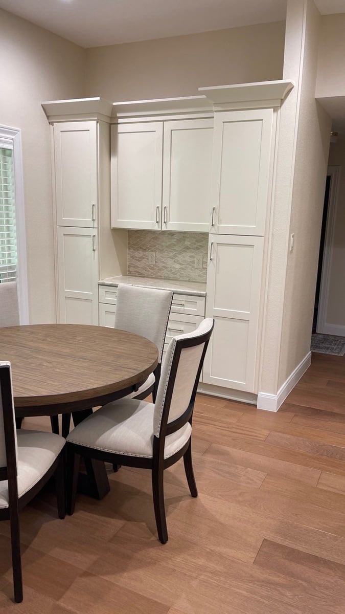 White pantry cabinets with marble desk nook beside round wood breakfast table