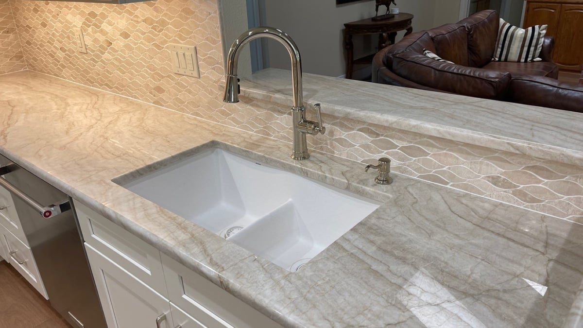 White composite sink in veined marble counter with nickel faucet and arabesque backsplash