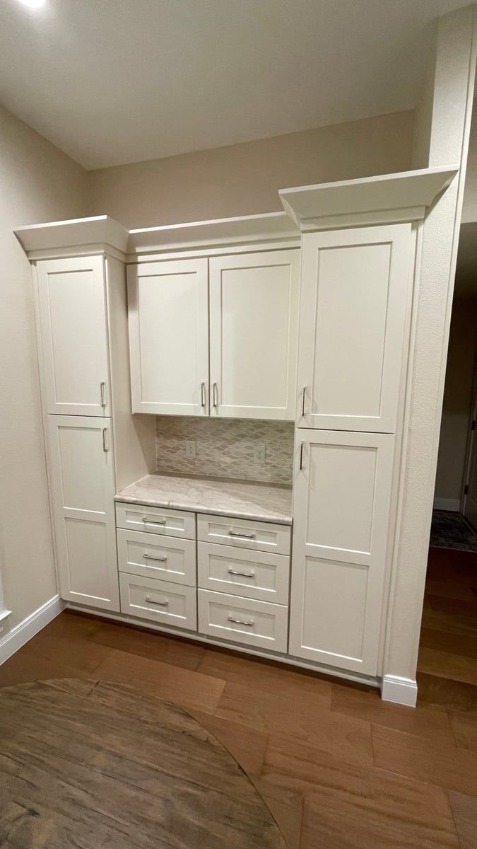 White hutch cabinet with marble counter and arabesque tile backsplash on wood floor