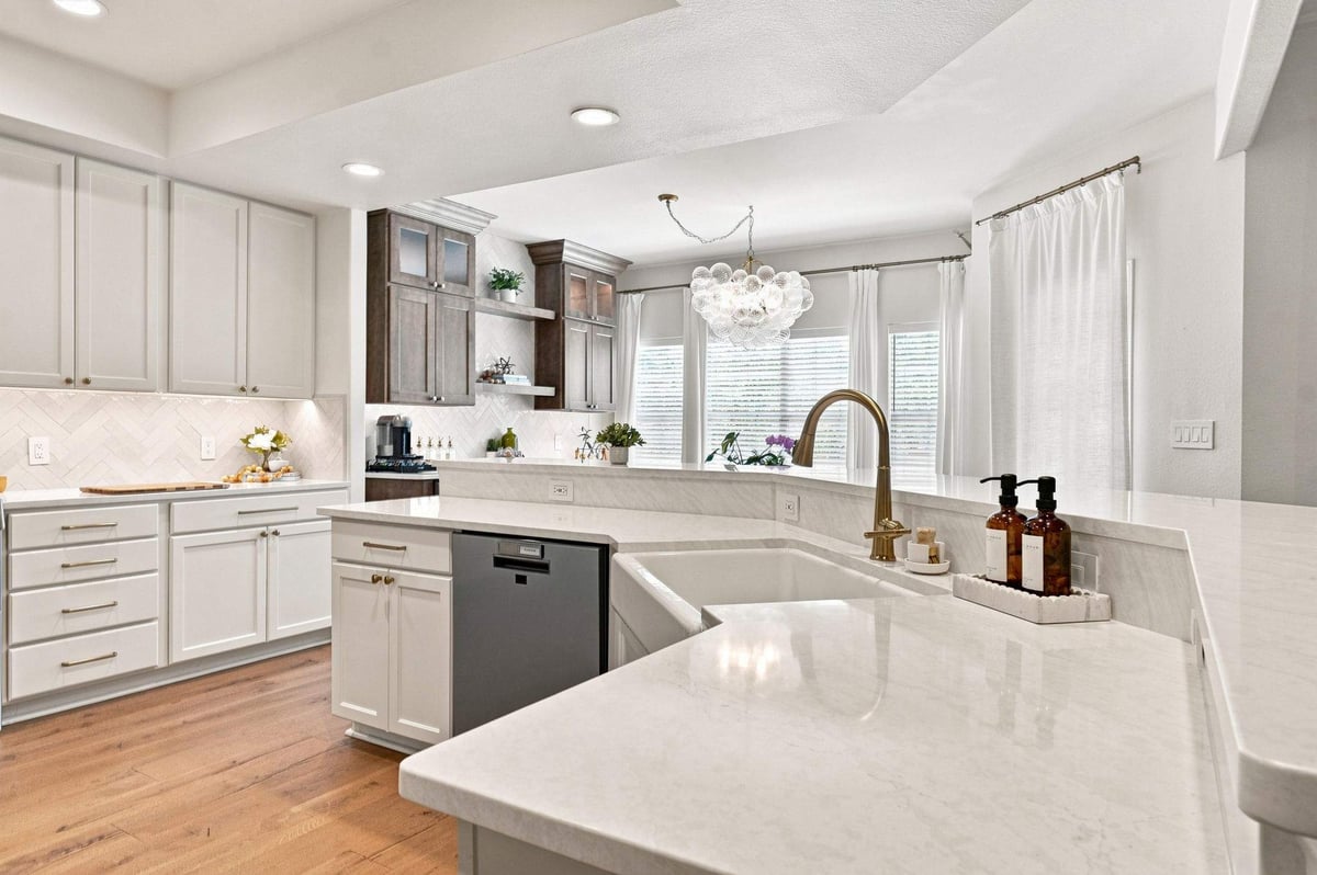 Open-plan kitchen with white island, wood accents, stainless steel appliances, and adjoining living area.