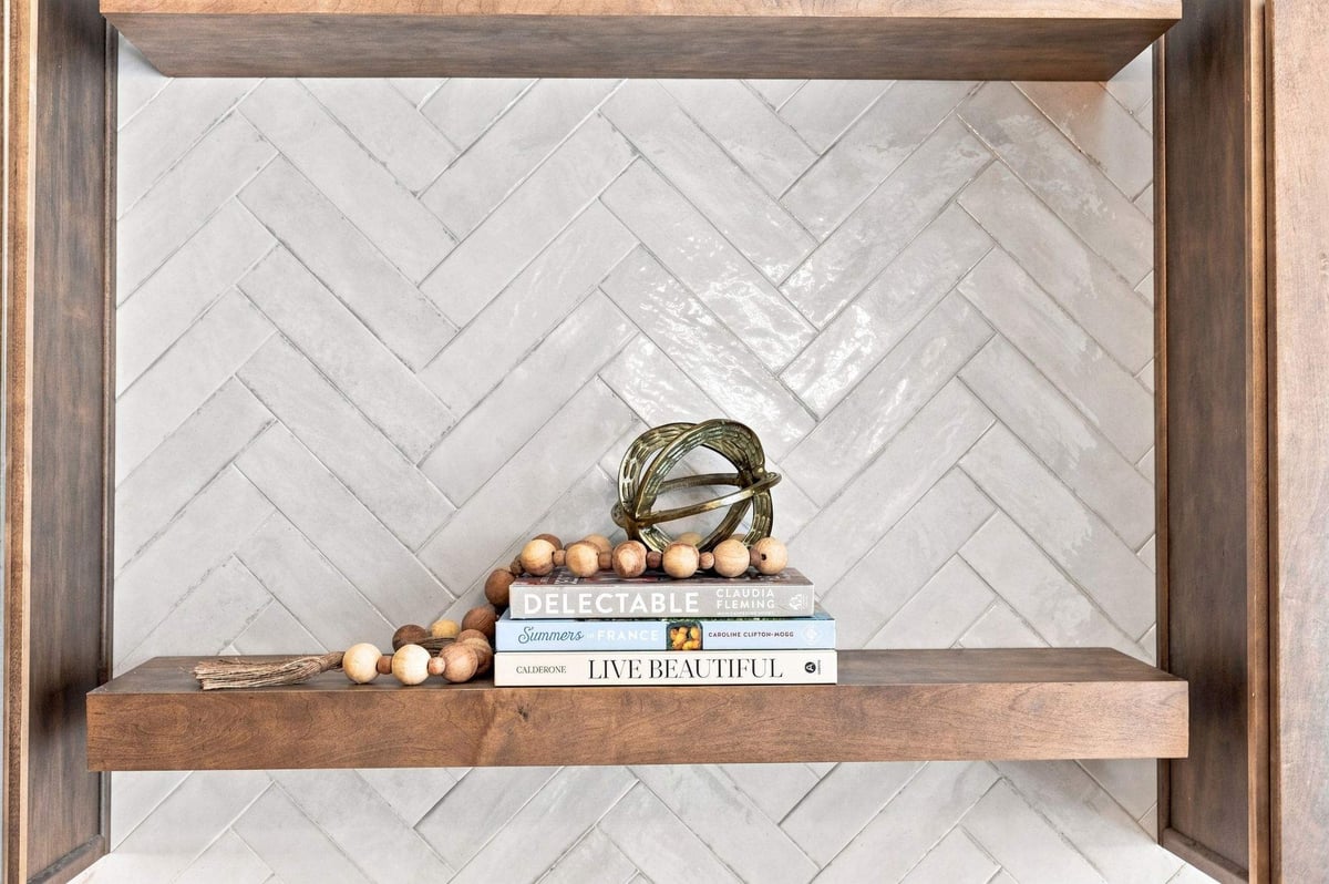 Close-up of floating shelf on herringbone tile backsplash.
