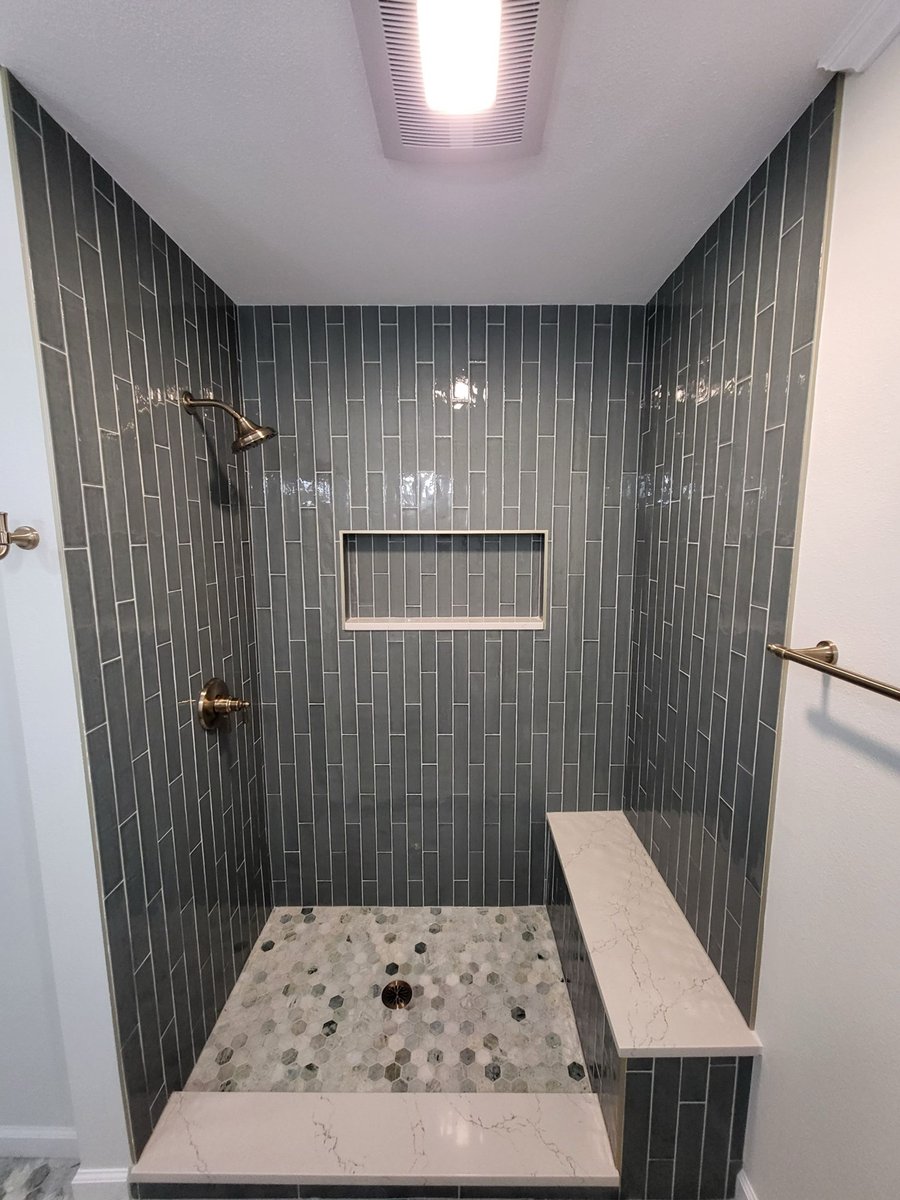Brushed gold rainfall shower head on blue subway tile shower wall