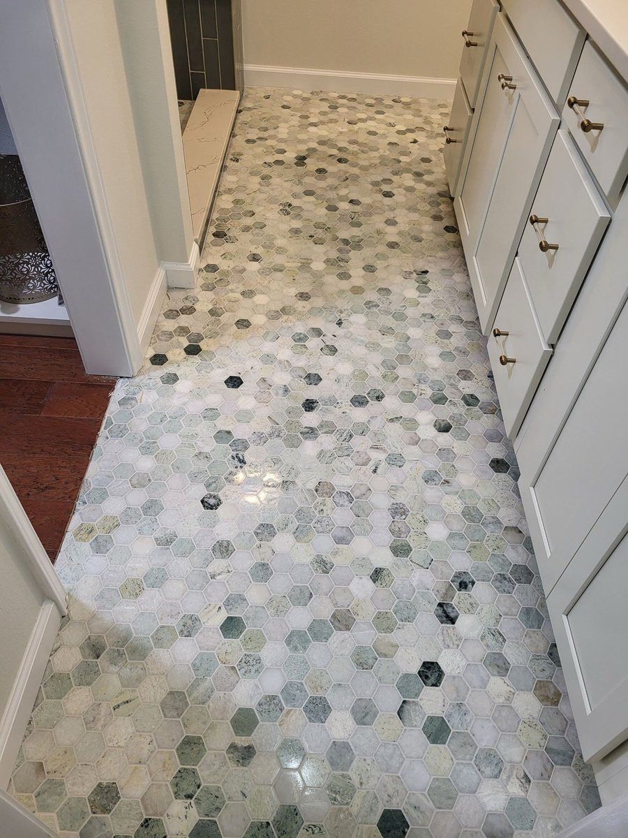 Walk-in shower with charcoal subway tile, marble bench, and glass block window