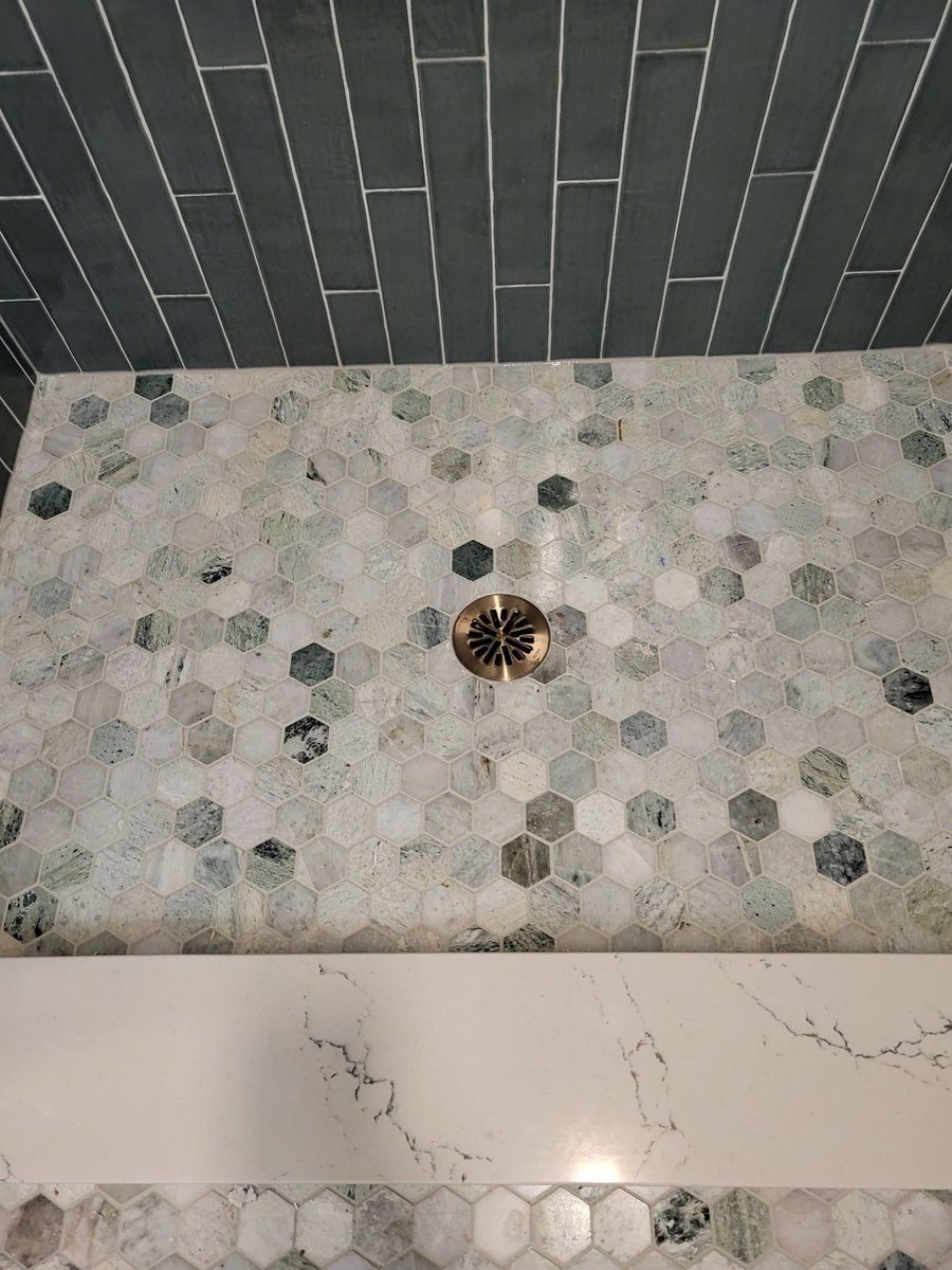 Blue-gray subway tile shower wall with niche and quartz bench seat