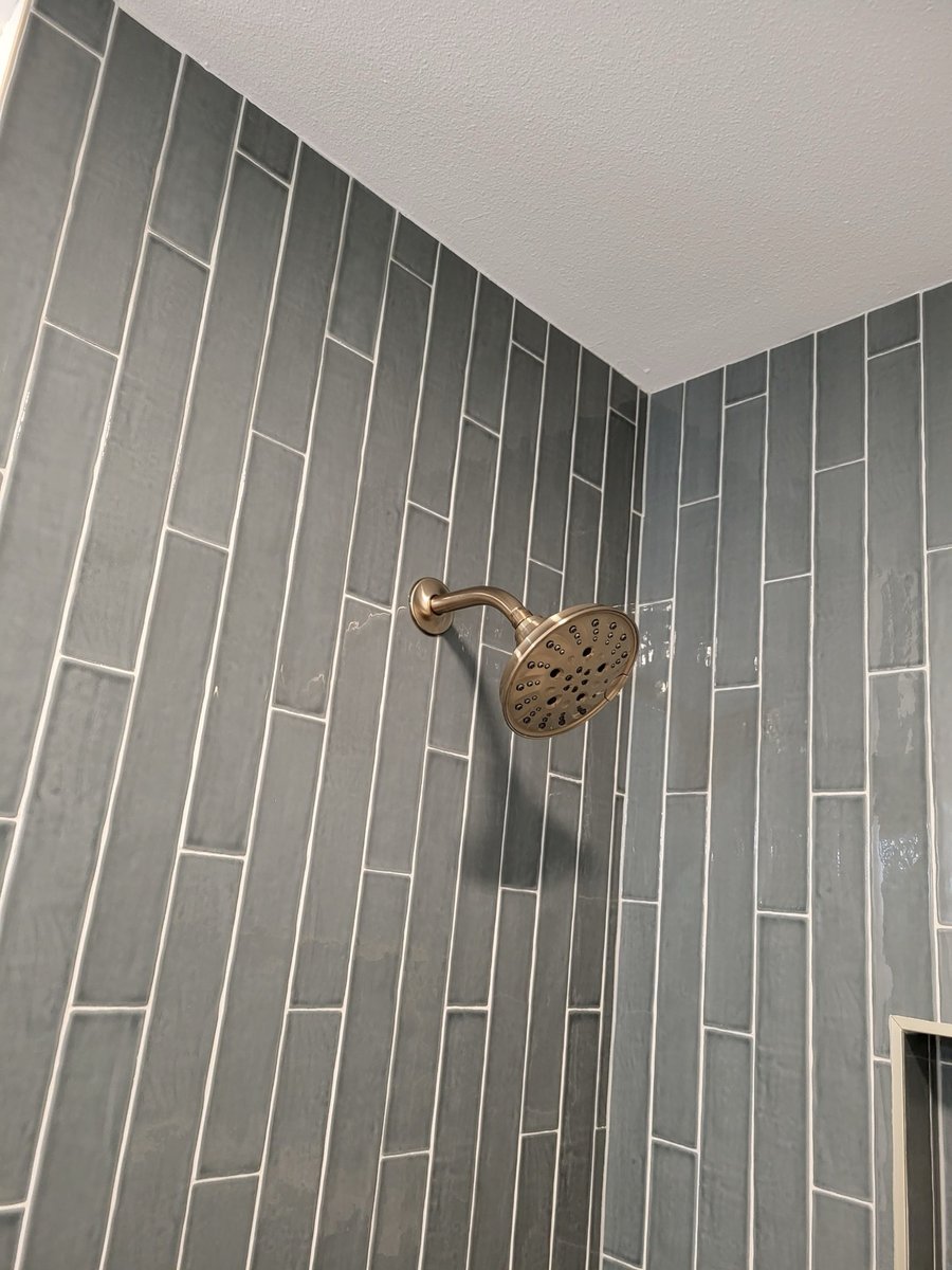 Charcoal tile shower with brass head, niche, and marble bench seat