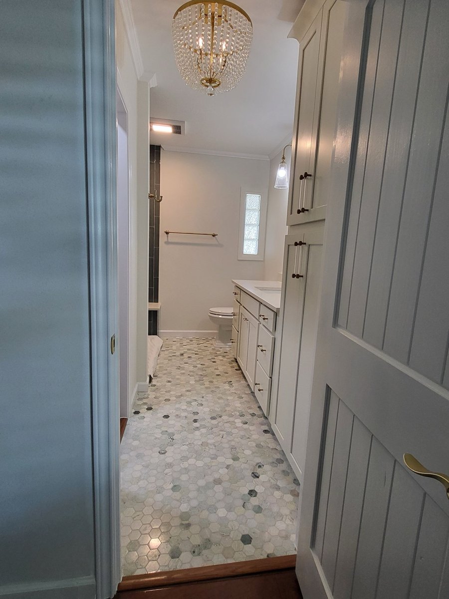 Gray glass tile shower with quartz bench and hexagon marble floor