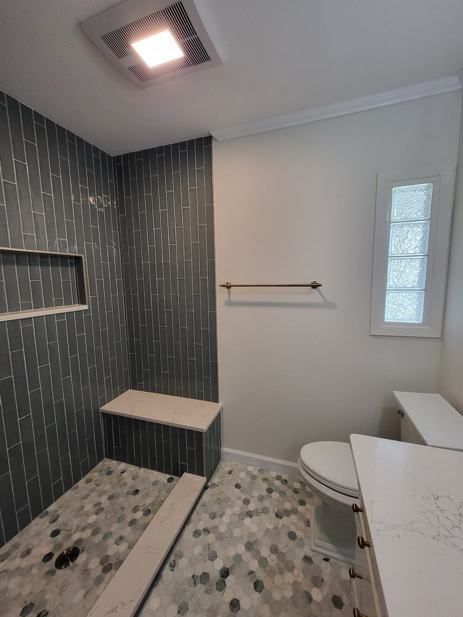 Bath floor view of hexagon marble tile beside white vanity cabinets