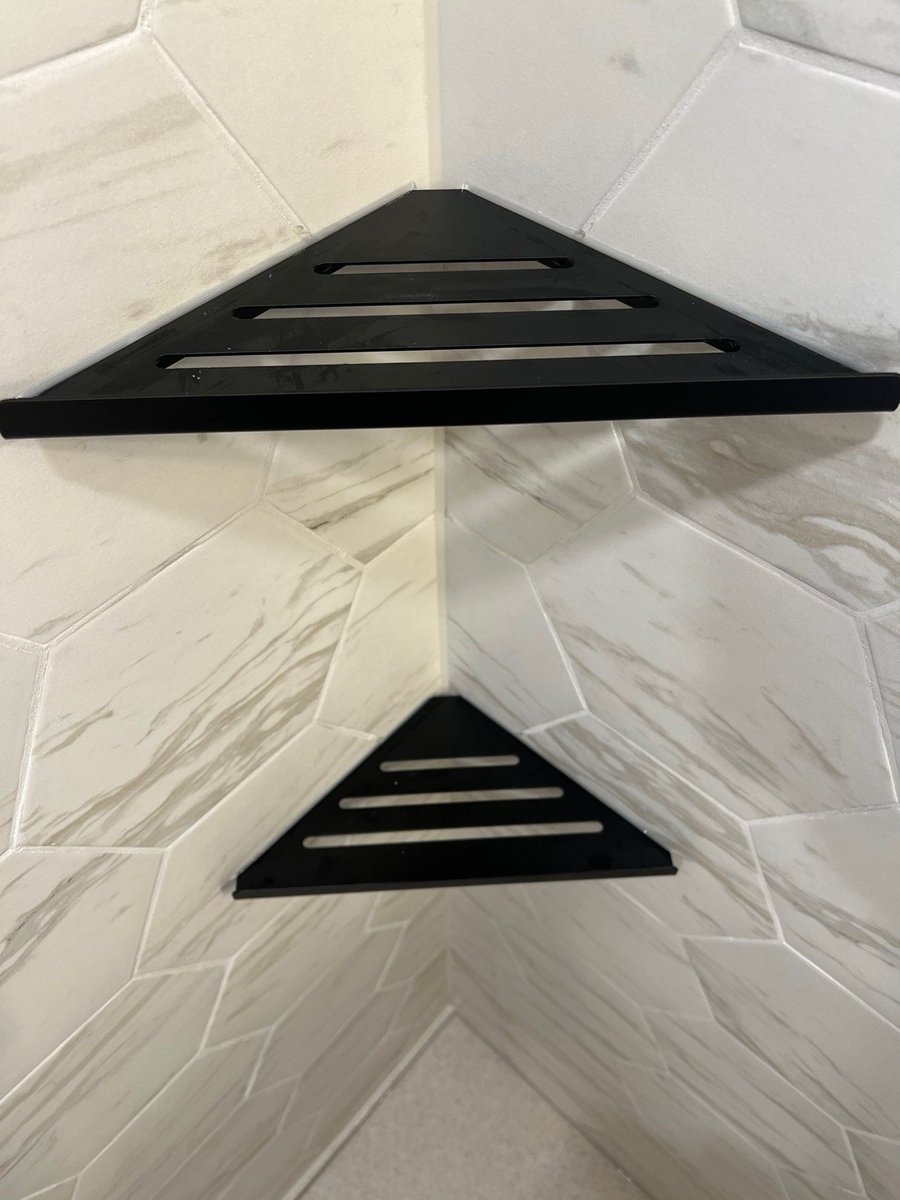 Black triangular corner shelves mounted on white marble hexagon shower tile