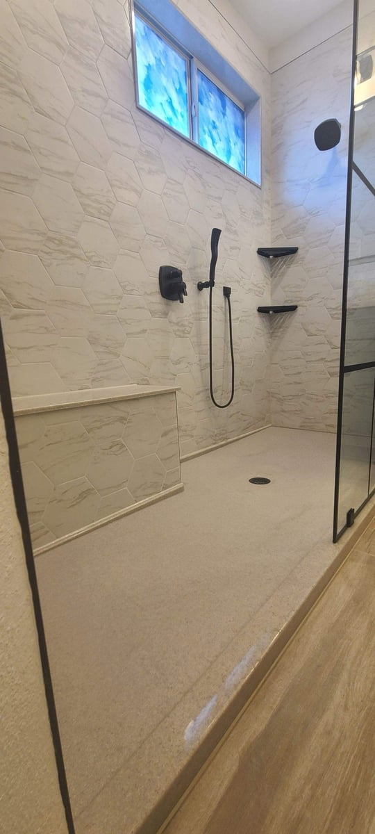 Walk-in shower with marble hexagon tile, black fixtures, and built-in bench