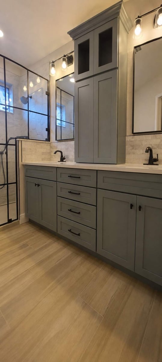 Gray vanity with dual sinks, marble subway backsplash, and glass shower with bench