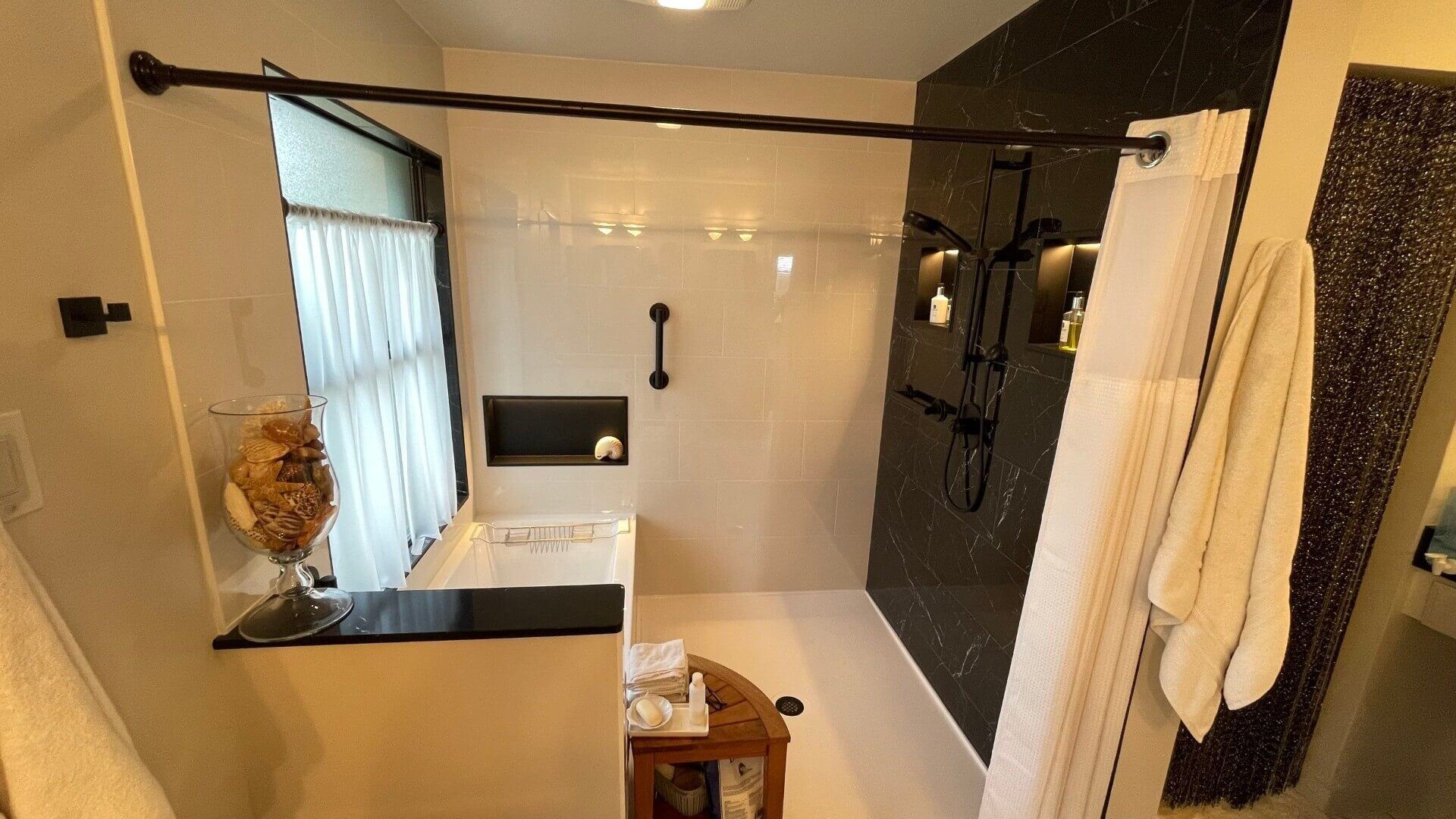 A modern bathroom remodel featuring a walk-in shower with dark tile accents, a sleek black shower fixture, and built-in storage niches for a minimalist, functional design.
