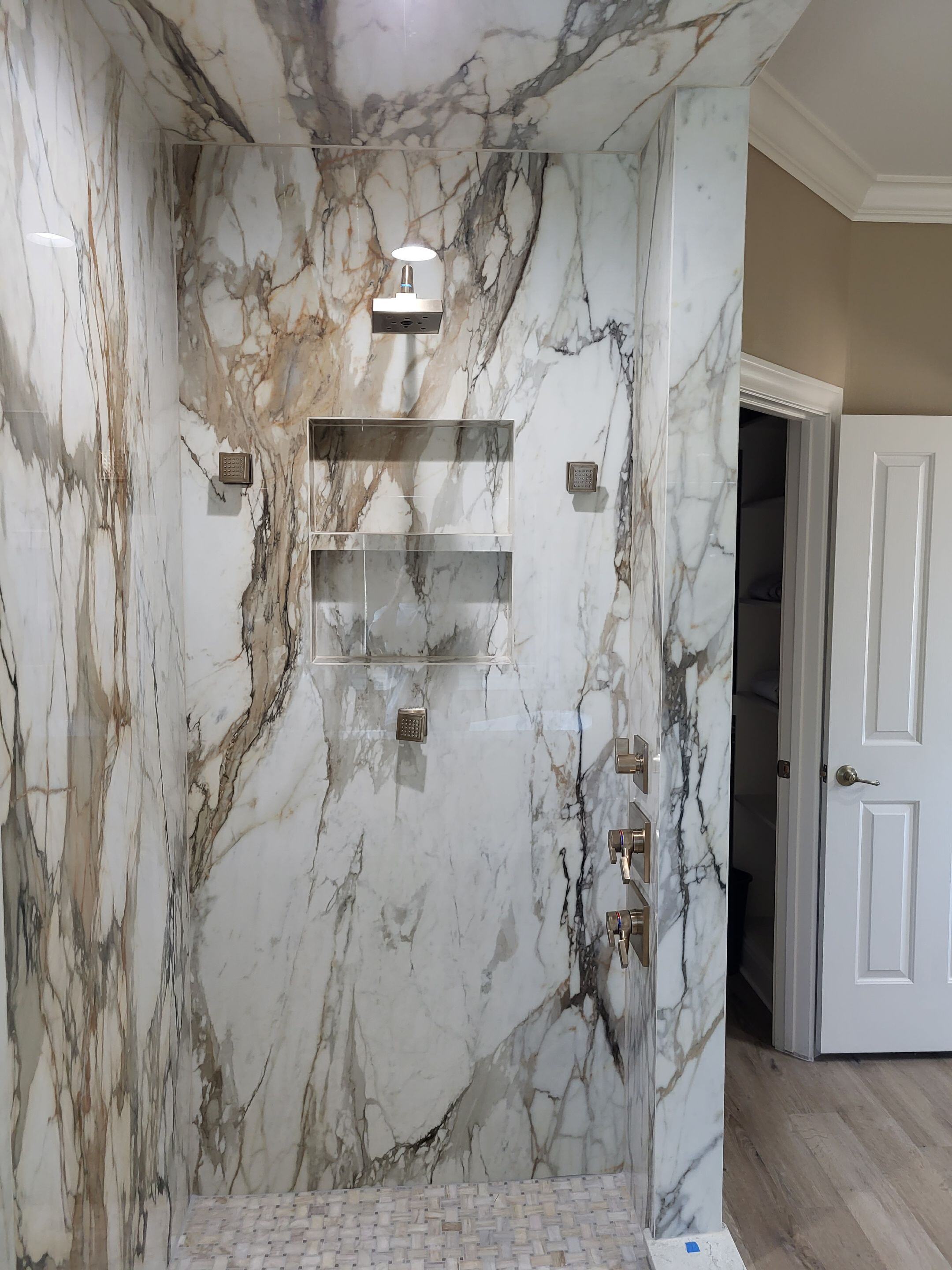 marble shower with gold fixtures in a primary bathroom renovation in san antonio