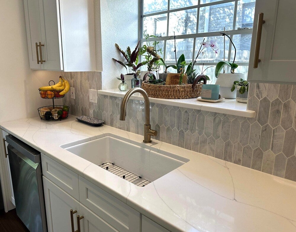 Kitchen sink with gold faucet and tile backsplash in San Antonio