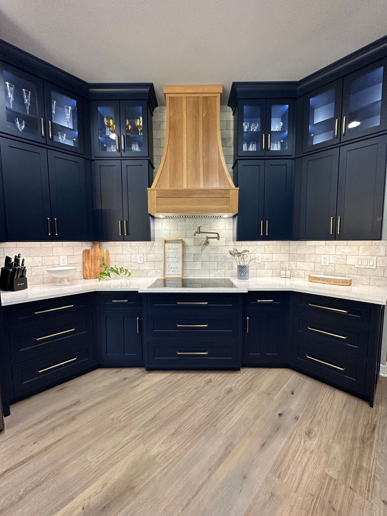 sandalwood kitchen floors, light wood kitchen hood, white counters, and blue kitchen cabinetry