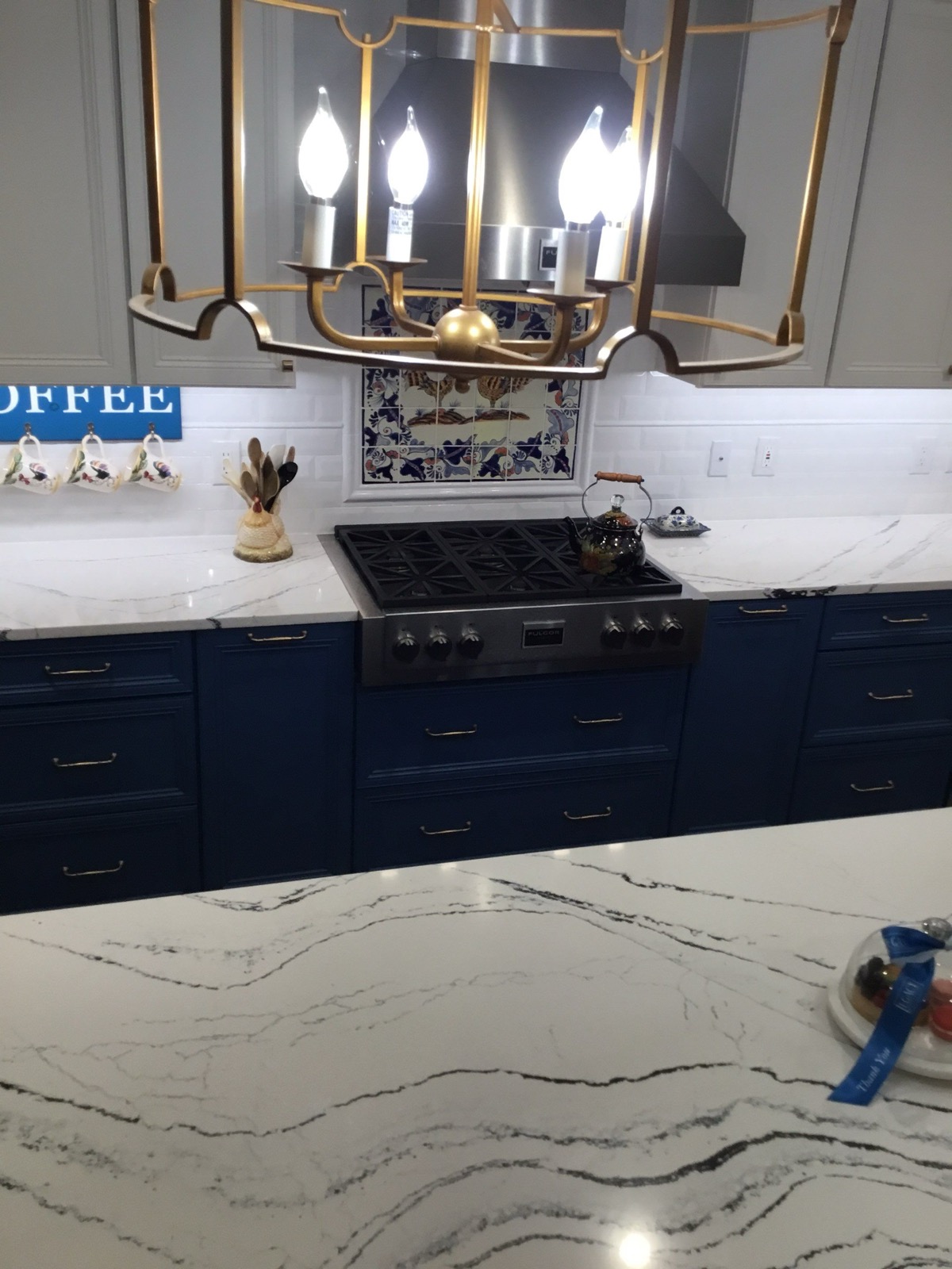 Veined white quartz counter beside gas cooktop and white subway backsplash Veined white quartz counter beside gas cooktop and white subway backsplash